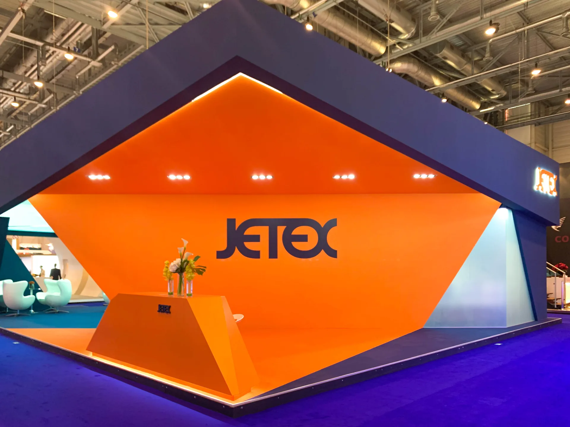 Jetex exhibition stand at EBACE Geneva, designed and built by Orchestra Media with a 540sqm orange-and-burgundy hero wall
